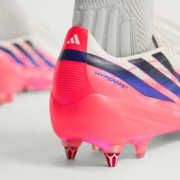 Близък план на бели футболни обувки adidas F50 Hyperfast Elite SG с бутони за мокър и кален терен от естествена трева 