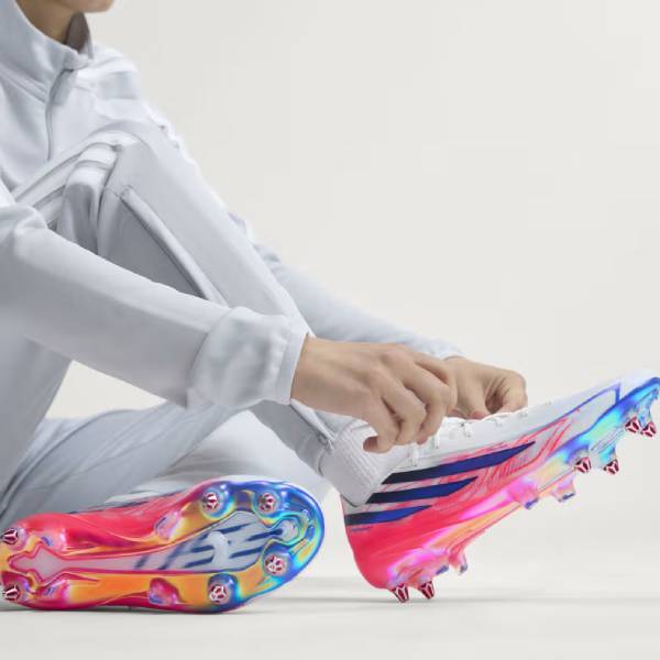 Близък план на бели футболни обувки adidas F50 Hyperfast Elite SG с бутони за мокър и кален терен от естествена трева 