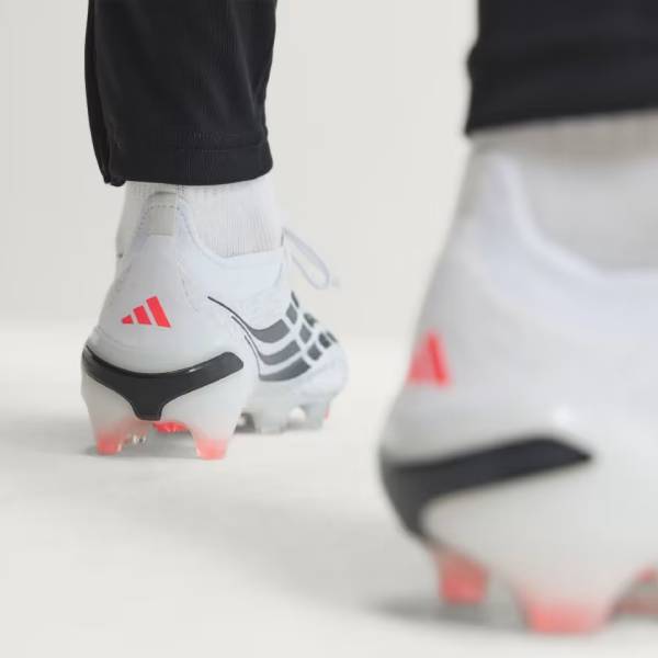 Близки план на бели футболни бутонки adidas Predator с ярки розово-червени ивици,
